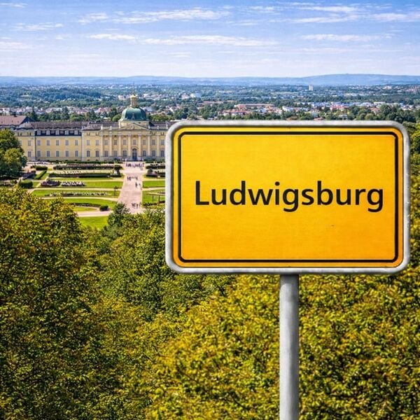 Gelbes Ortsschild Ludwigsburg mit Stadt im Hintergrund