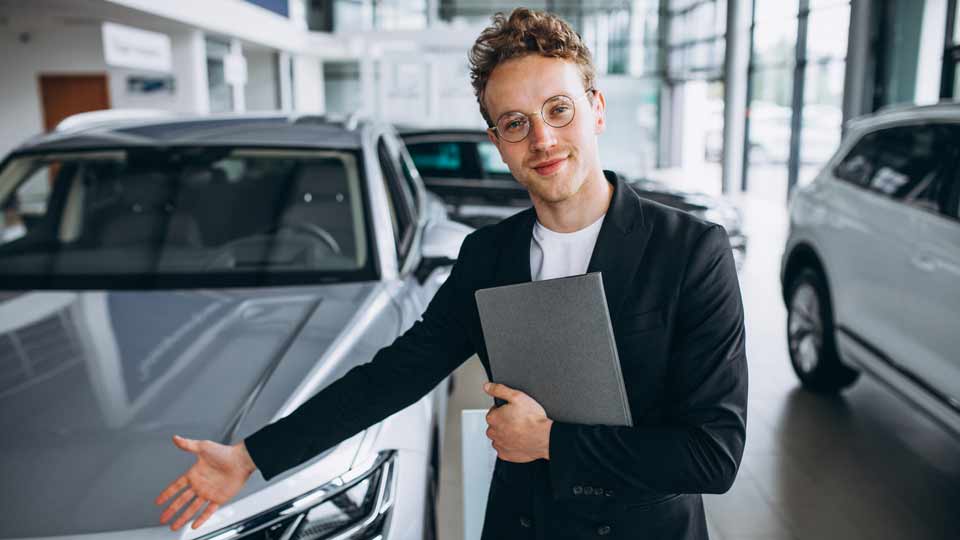 Ein Verkäufer zeigt auf ein Auto und erklärt dem Kunden die Konditionen beim Auto verkaufen Ludwigsburg